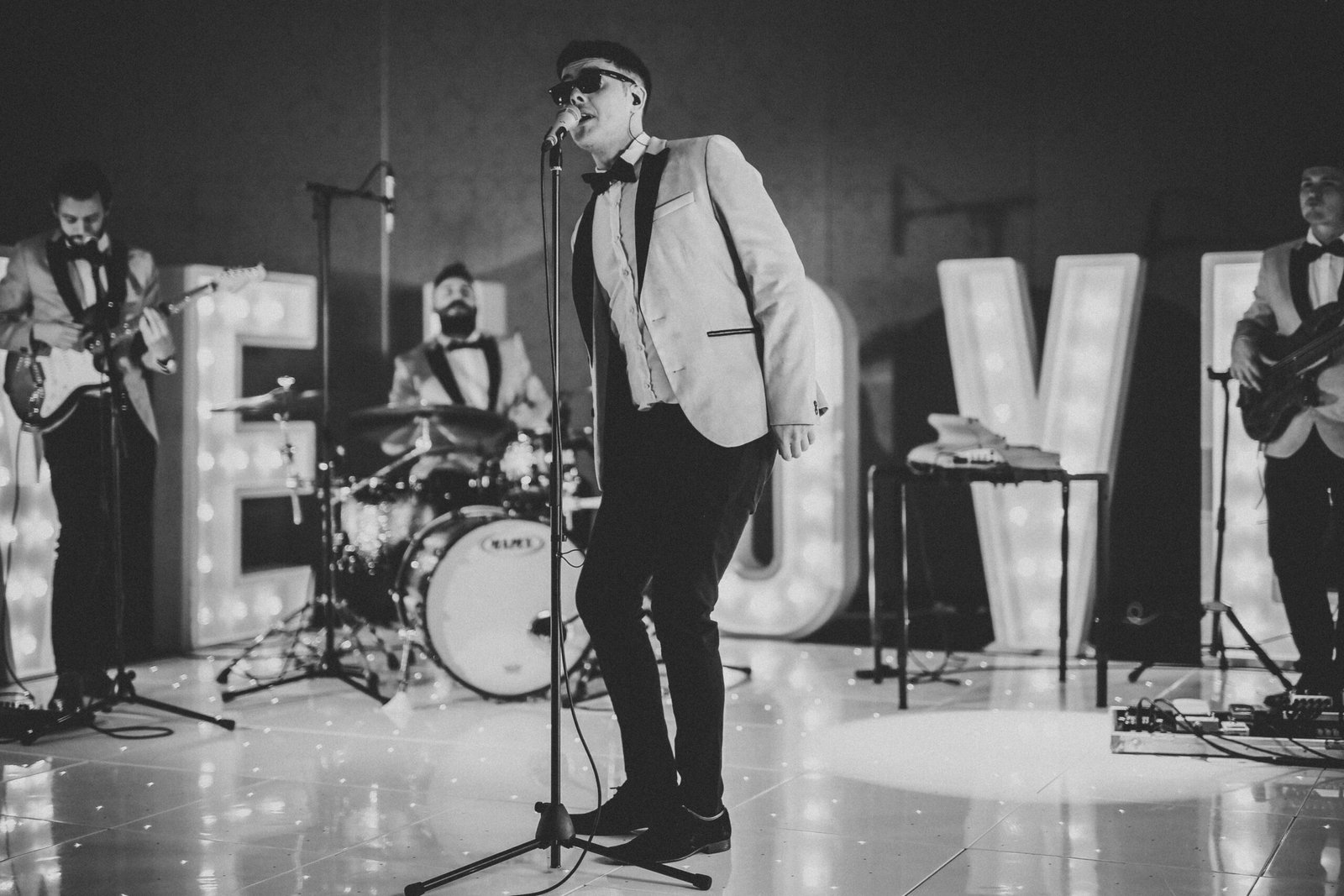 man in white suit standing on stage